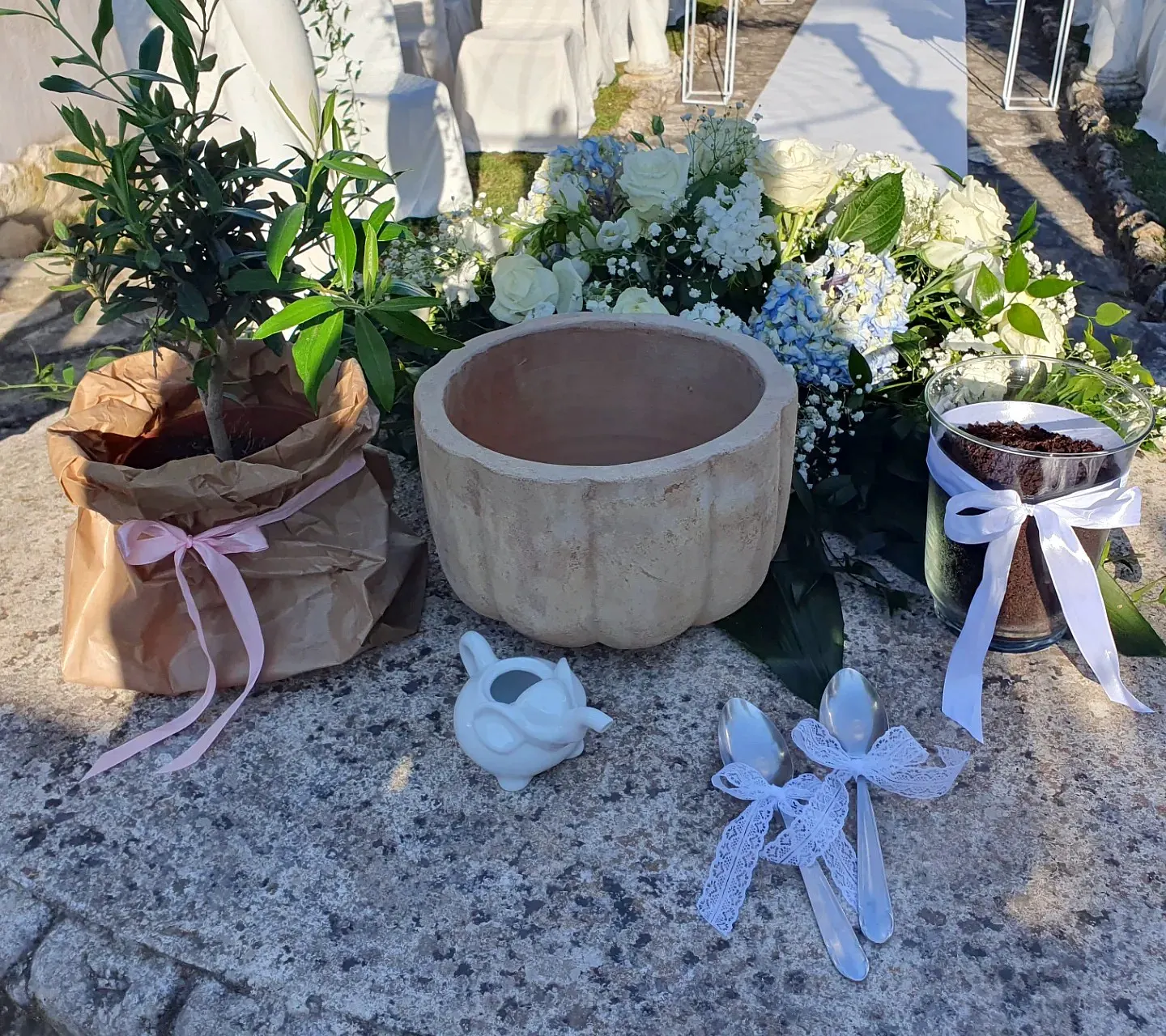 Olivo, vaso in pietra, barattolo di terra e cucchiai con fiocchi pronti per il rito dell'albero Olivo, vaso in pietra, barattolo di terra e cucchiai con fiocchi pronti per il rito dell'albero