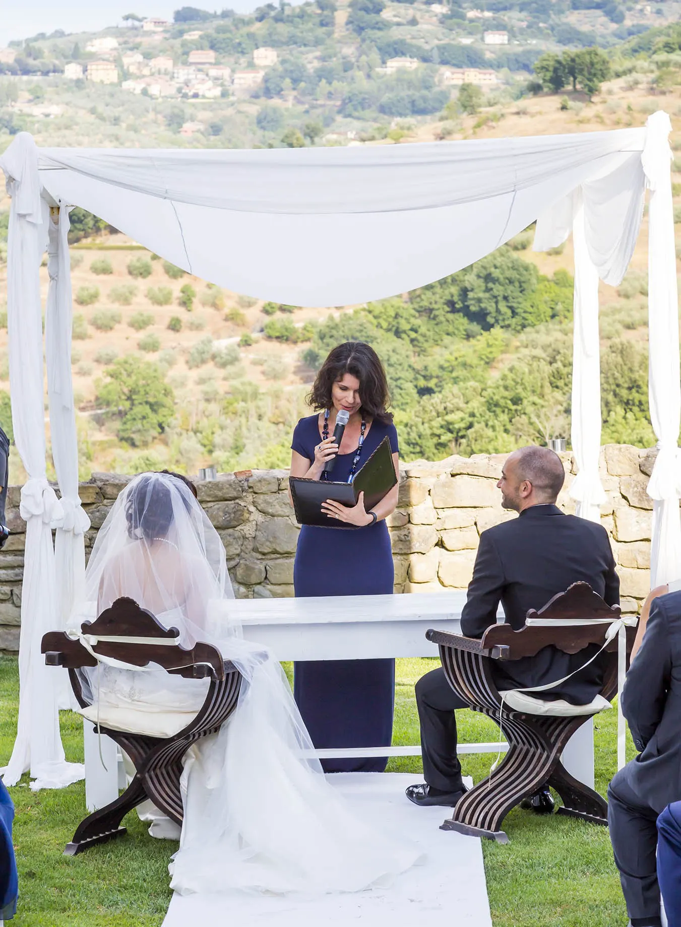Photo: Rellini Art Studio Celebrant reading the ceremony under a white canopy with the Tuscan hills behind