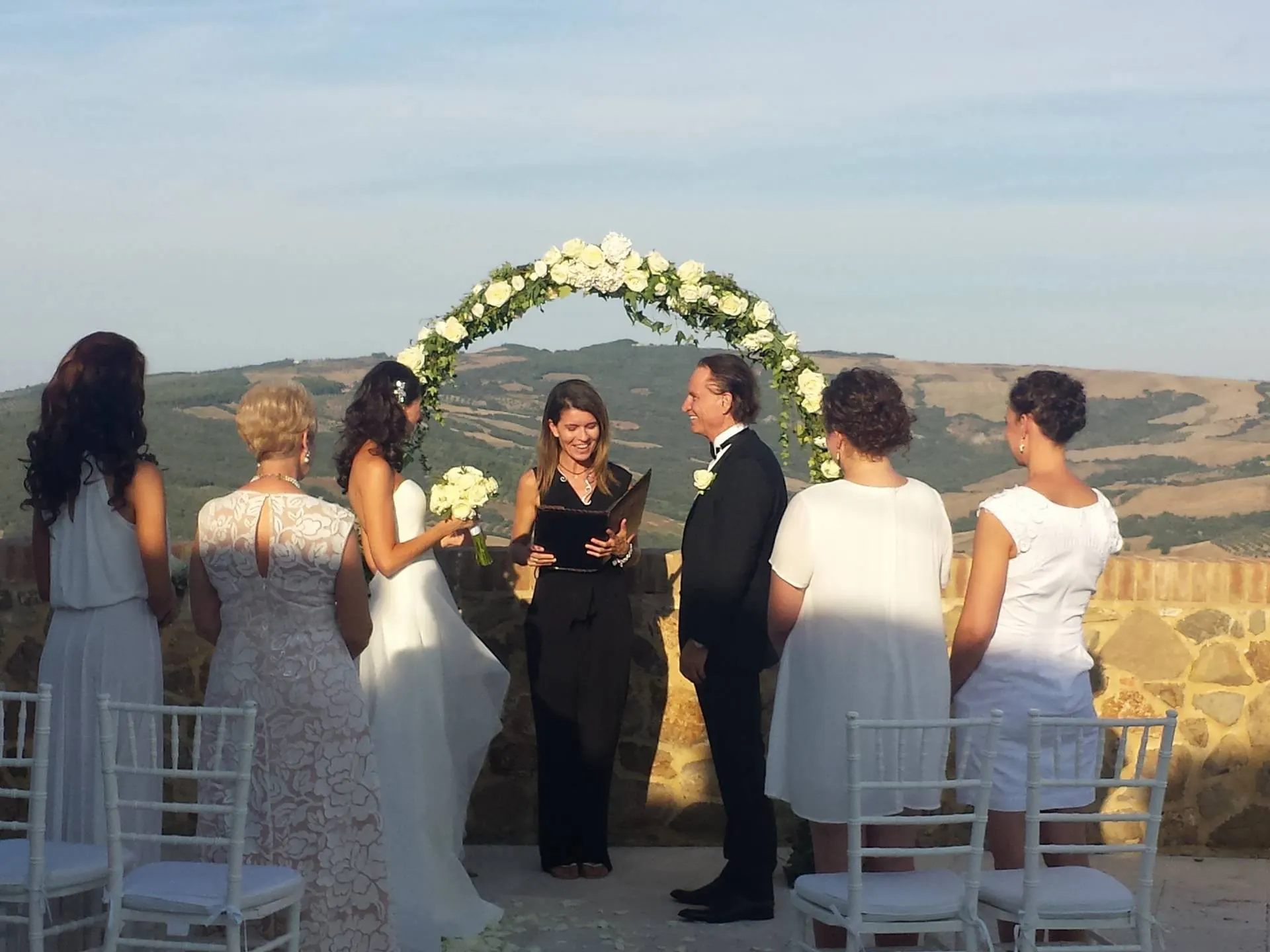 Wedding ceremony under a white rose arch with a view of the Val d'Orcia Wedding ceremony under a white rose arch with a view of the Val d'Orcia