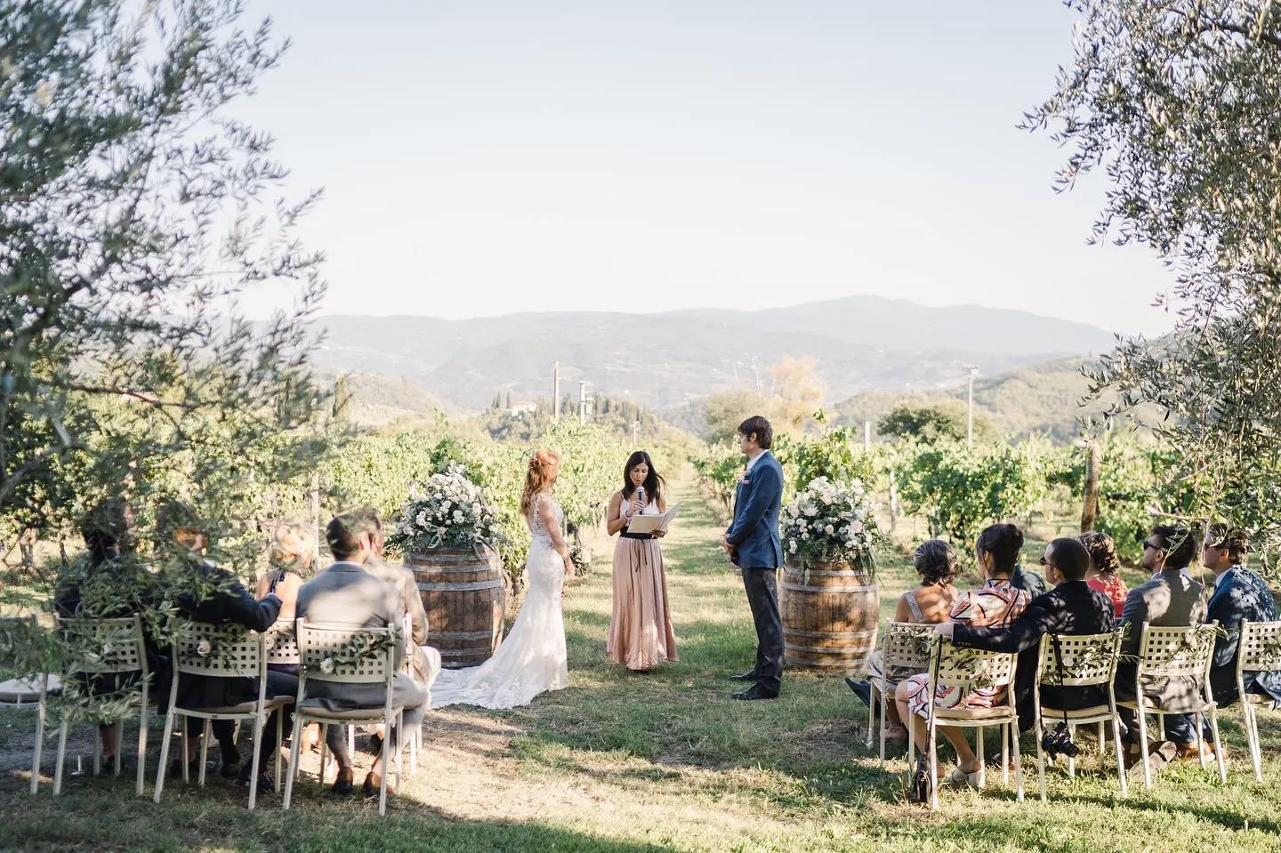 Wedding celebrants in Tuscany Wedding ceremony in a vineyard with guests seated among olive trees