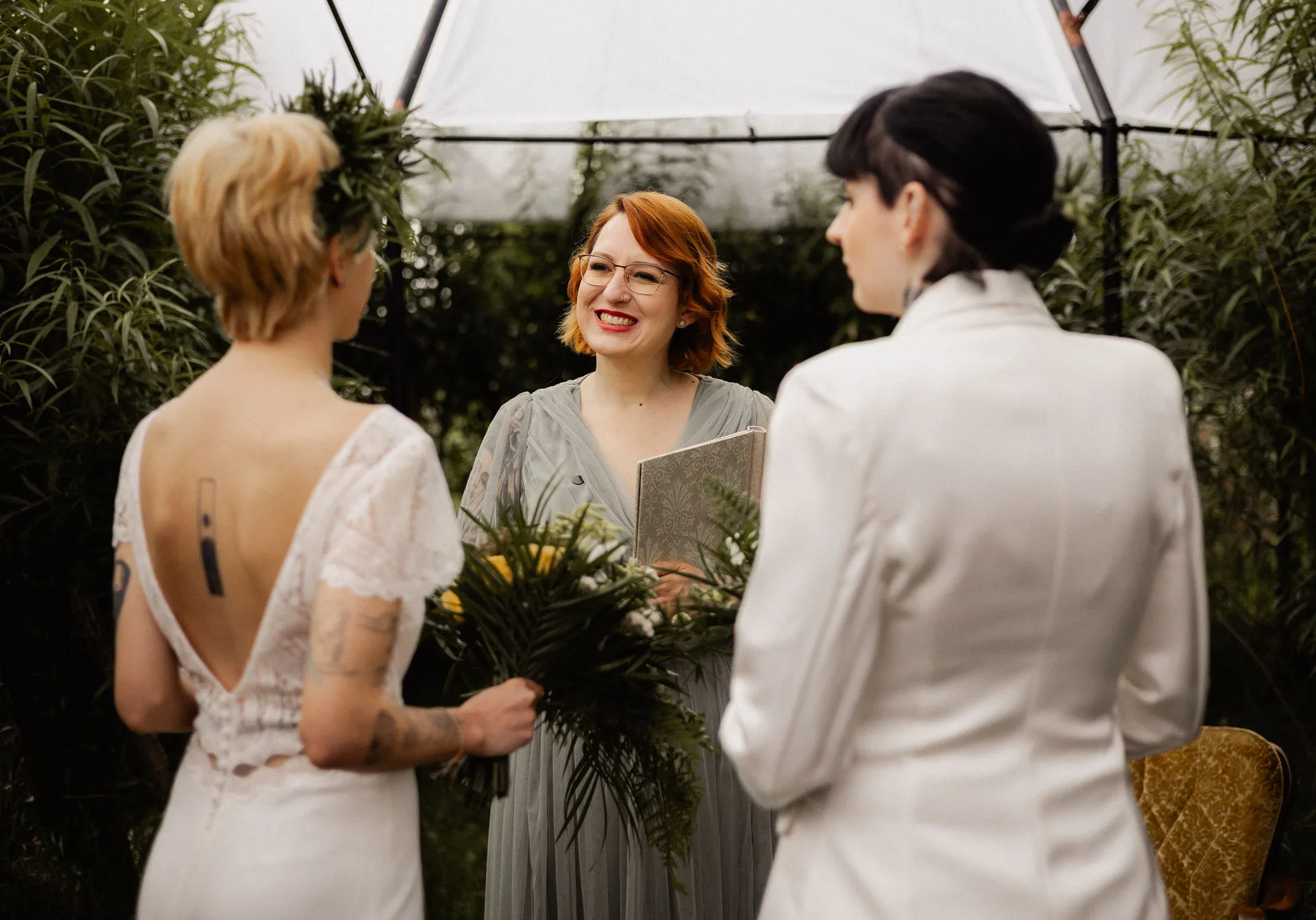 Cora Cora smiling while leading a garden wedding ceremony